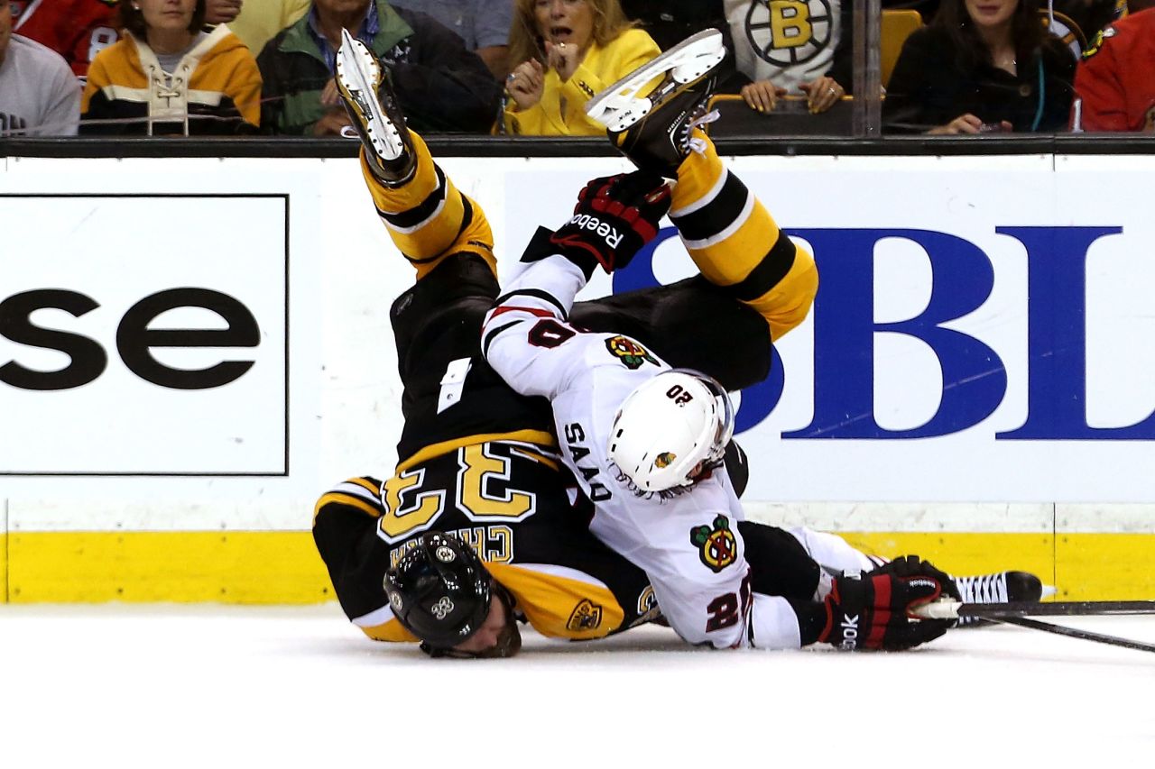 Zdeno Chara of the Boston Bruins and Brandon Saad of the Chicago Blackhawks fall to the ice.