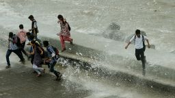 Pedestrians run from water splashing over a sea wall in Mumbai on Monday, June 24.  Authorities are scrambling to rescue thousands of people trapped after floods and landslides ravaged north India, leaving up to 1,000 feared dead. 
