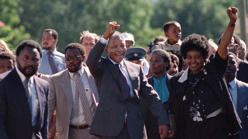 (FILES) A picture taken on February 11, 1990 shows Nelson Mandela (C) and his then-wife Winnie raising their fists and saluting cheering crowd upon Mandela's release from the Victor Verster prison near Paarl. Rolihlahla Dalibhunga Mandela, affectionately known by his clan name "Madiba", became commander-in-chief of Umkhonto weSizwe (Spear of the Nation), the armed underground wing of the African National Congress, in 1961, and the following year underwent military training in Algeria and Ethiopia. After more than a year underground, Mandela was captured by police and sentenced in 1964 to life in prison during the Rivonia trial, where he delivered a speech that was to become the manifesto of the anti-apartheid movement. Mandela started his prison years in the notorious Robben Island Prison, a maximum security prison on a small island 7Km off the coast near Cape Town. In April 1984 he was transferred to Pollsmoor Prison in Cape Town and in December 1988 he was moved the Victor Verster Prison near Paarl. While in prison, Mandela flatly rejected offers made by his jailers for remission of sentence in exchange for accepting the bantustan policy by recognising the independence of the Transkei and agreeing to settle there. Again in the 'eighties Mandela rejected an offer of release on condition that he renounce violence. Prisoners cannot enter into contracts. Only free men can negotiate, he said, according to ANC reports.  AFP PHOTO FILES / ALEXANDER JOE (Photo credit should read ALEXANDER JOE/AFP/Getty Images)