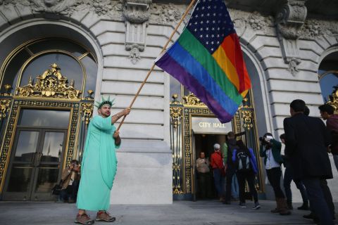 A gay rights supporter waves a flag outside City Hall in San Francisco ahead of the Supreme Court decisions on June 26.