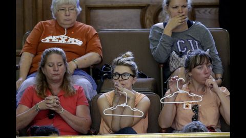 Opponents of the bill sit in the gallery holding hangers.