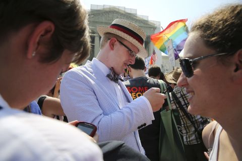 Same-sex marriage proponent Ryan Clarke reads news updates on the rulings outside of the Supreme Court.