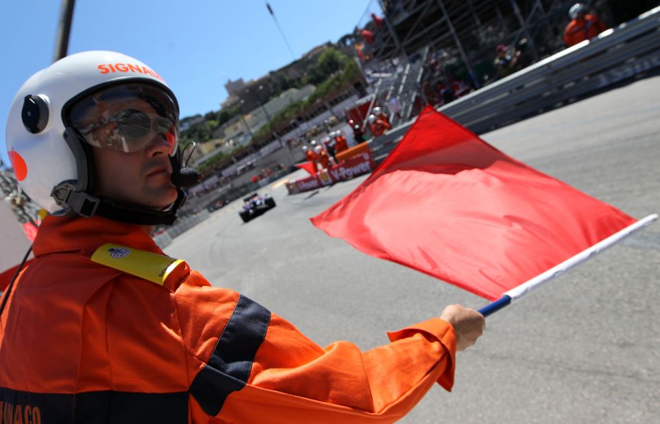 Some of the marshals communicate messages from race control to the Formula One drivers. Here a red flag, shown at the Monaco Grand Prix, means the track session has been stopped.