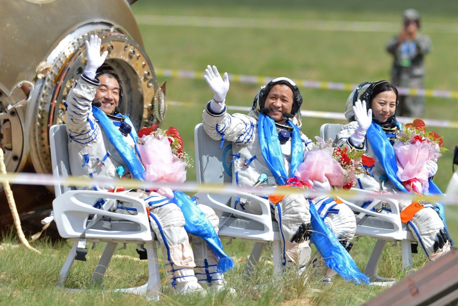 Astronauts wave after getting out from the return capsule of the Shenzhou-10 spacecraft after completing China's longest manned space mission on June 26, 2013.