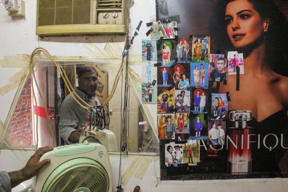 Salim, a 43-year old refugee from Bangladesh, stands before a wall of family pictures in the slum of Ping Che, Hong Kong on June 25, 2013. Salim, a former business owner, fled Bangladesh after terrorists threatened to kill him. They have also threatened his wife and son, who is now 19, he said. 