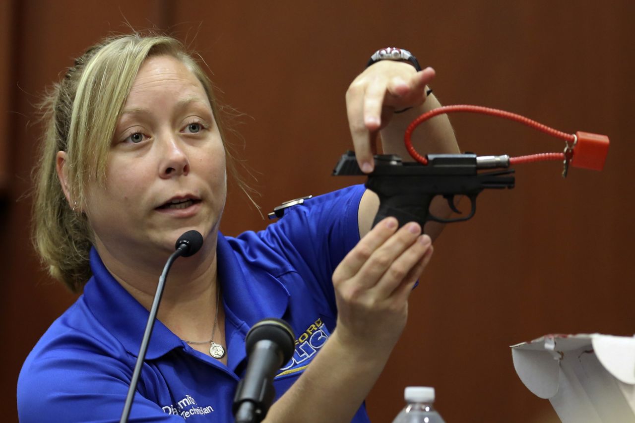 During the trial on June 25, crime scene technician Diana Smith shows the jury a gun that was collected as evidence.