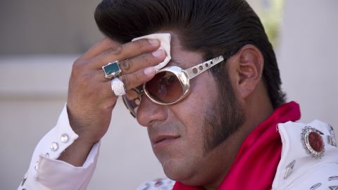 Elvis impersonator Cristian Morales wipes sweat from his brow while posing for photos with tourists on the Las Vegas Strip on Thursday, June 27.