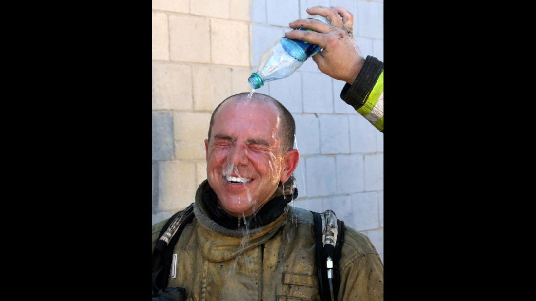 A Salt Lake City fireman pours water over the head of fireman Cary Turner after battling a house fire on Wednesday, June 26. Temperatures in Utah are approaching record highs.