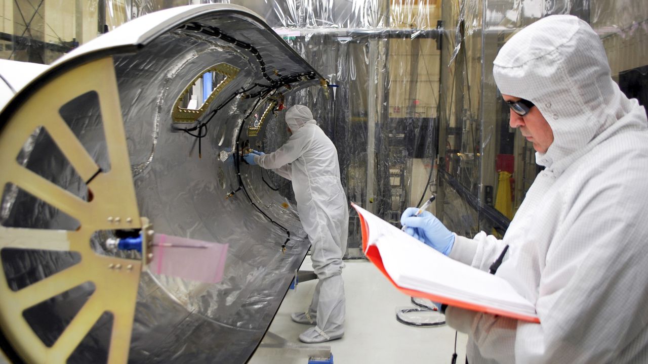 Technicians work on the payload fairing built to protect the IRIS spacecraft during launch aboard an Orbital Sciences Pegasus XL rocket.