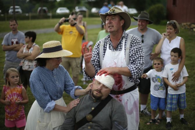 Spectators watch as reenactors portray medical treatment at a Confederate field hospital at the Daniel Lady Farm in Gettysburg.