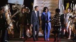 PRETORIA, SOUTH AFRICA - JUNE 28: U.S. President Barack Obama (L) and first lady Michelle Obama (C) are greeted by Minister of International Relations and Cooperation Maite Mkoana-Mashabne after arriving at Waterkloof Air Force Base June 28, 2013 in Pretoria, South Africa. This is Obama's first official visit to South Africa, where is schedule to hold bilaterial meetings with President Jacob Zuma, host a town hall meeting with students in Soweto Township and visit Robben Island, where former President Nelson Mandela spent some of his 27 years in prison for fighting against apartheid. (Photo by Chip Somodevilla/Getty Images)