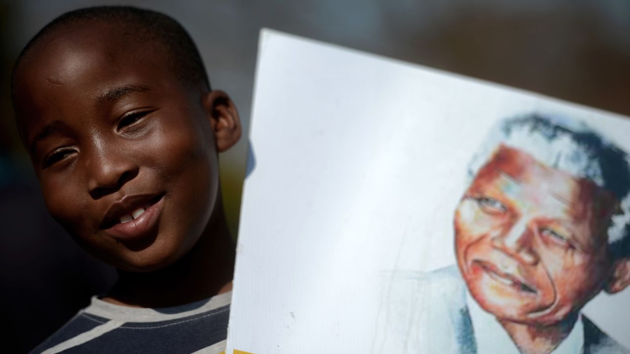 A child holds a portrait of Nelson Mandela in Pretoria, South Africa.
