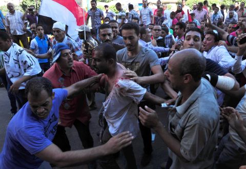 Egyptians help a wounded man following clashes between Morsy's supporters and opponents in Alexandria on June 28.