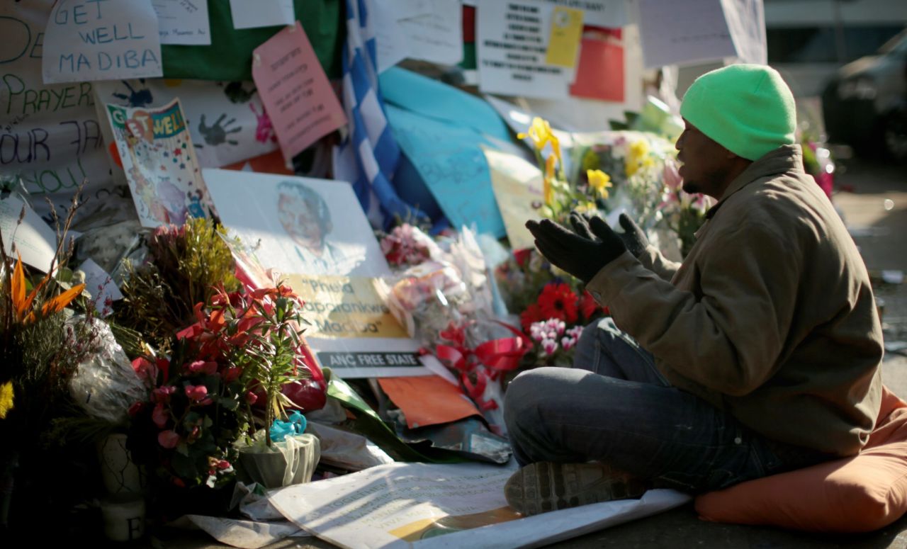 A man prays at the tribute wall for Mandela outside the hospital on June 30.