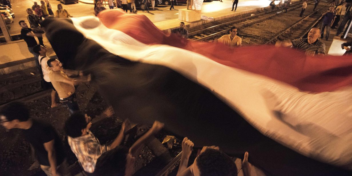 Morsy opponents wave a giant national flag outside the presidential palace on Saturday, June 29.
