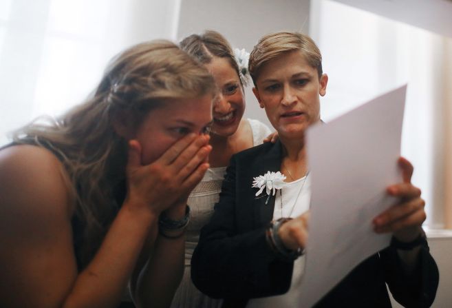 Stefanie Berks, center, and Daisy Boyd, right, view their marriage certificate with a friend after their ceremony in the east chapel at the Manhattan Marriage Bureau on June 28.