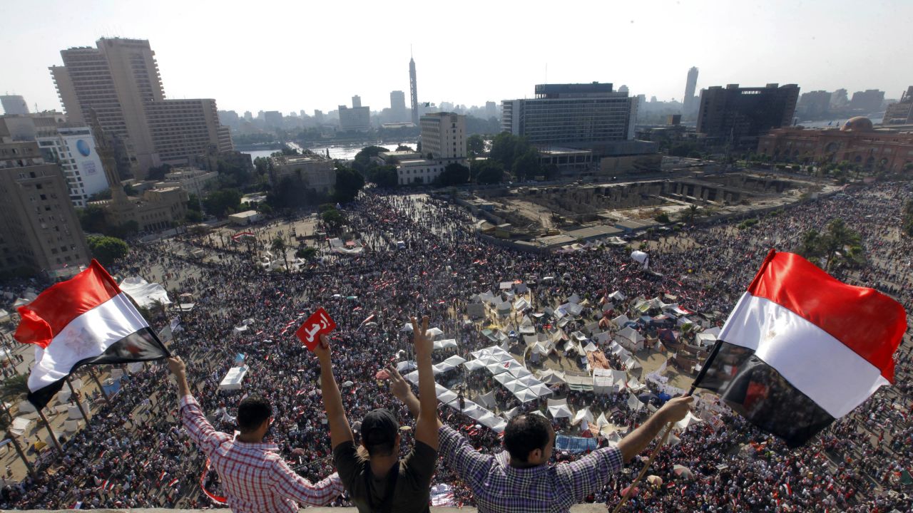 Protesters wave national flags and a red card in Arabic reading "leave" in Tahrir Square during the June 30 demonstrations against Morsy.