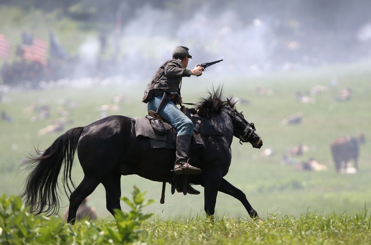 A Confederate Civil War cavalry reenactor shoots at Union soldiers during Pickett's Charge on the last day of a Battle of Gettysburg reenactment on Sunday, June 30, during 150th anniversary celebrations in Gettysburg, Pennsylvania. More than 10,000 reenactors will pay tribute to the major clashes that took place in the pivotal Civil War battle in July 1863.