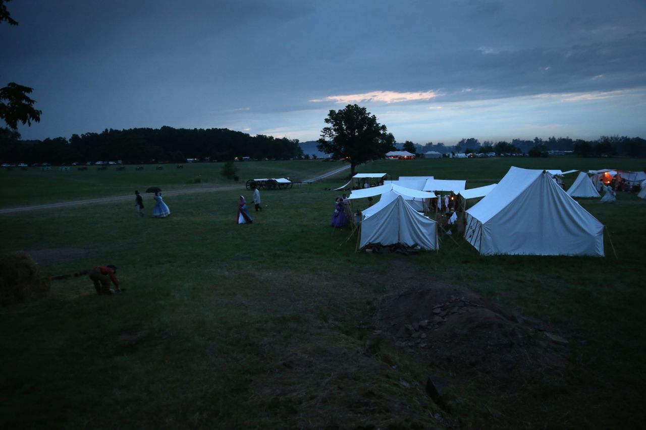 Reenactors take shelter from an evening rain storm in tents on June 29. 