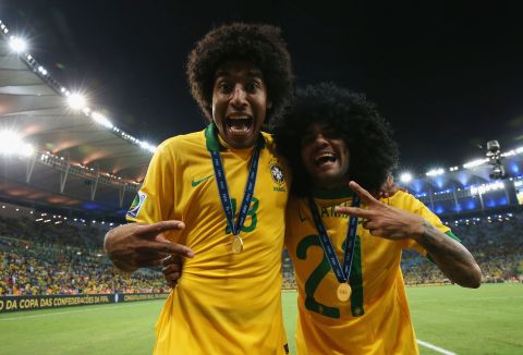Brazil players Dante, left, and Dani Alves, in a wig, celebrate with their winner's medals.
