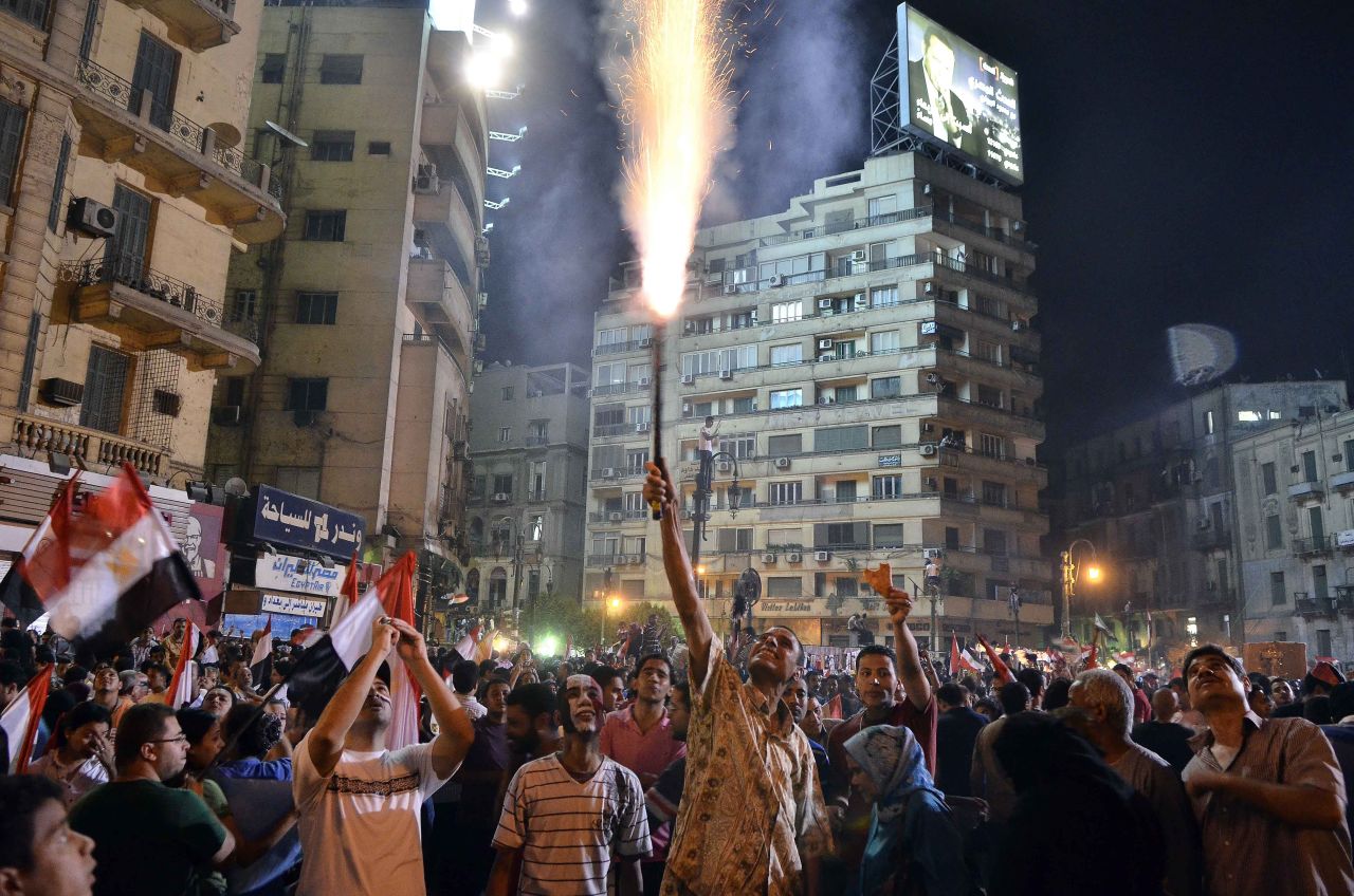 A protester lights a flare as hundreds of thousands of demonstrators gather in Cairo's landmark Tahrir Square on July 1 during a protest calling for the ouster of Morsy.