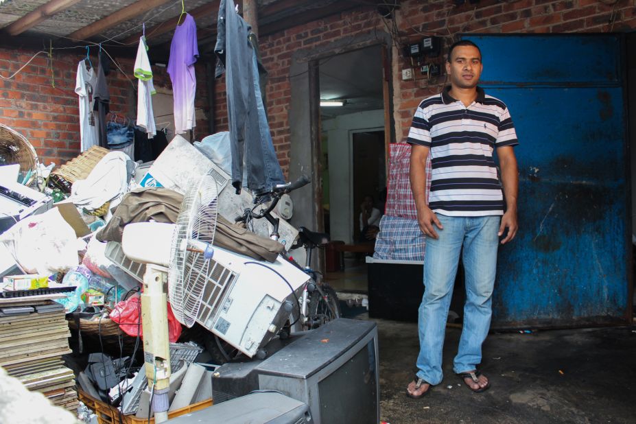 Johir, a refugee from Bangaldesh, stands next to a pile of salvaged objects in the slum village of Ping Che on June 25, 2013. Because asylum seekers are forbidden to make money while awaiting a status determination, Johir must gather clothes and household items from a nearby garbage dump.