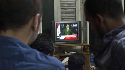 People watch Morsy on television in Cairo on Tuesday, July 2.