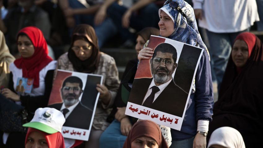Egyptian supporters of President Mohamed Morsi hold posters bearing his portrait during a rally outside Cairo University on June 3, 2013. Egyptian security forces imposed a travel ban on President Mohamed Morsi and several top Islamist allies over their involvement in a prison escape in 2011, security officials said. AFP PHOTO / KHALED DESOUKIKHALED DESOUKI/AFP/Getty Images