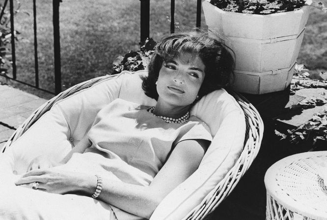 Photo of US First Lady Jacqueline Kennedy relaxing in a chair, wearing a pearl necklace, a few weeks after her husband John F. Kennedy won the US presidential election. 