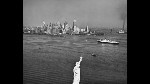 The towering skyline of downtown Manhattan is seen behind the statue in 1950.