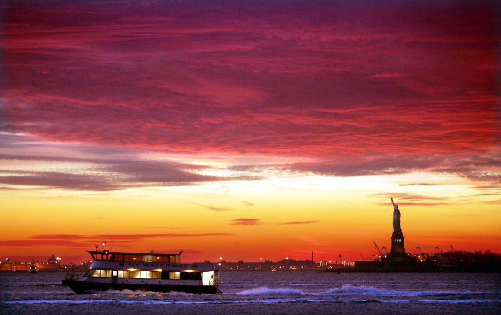 A New York Waterway ferry moves along the water as the sun sets behind the Statue of Liberty in 2004.