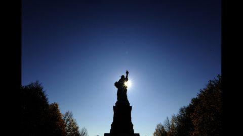 The sun rises in front of the Statue of Liberty before the start of ceremonies on October 28, 2011.