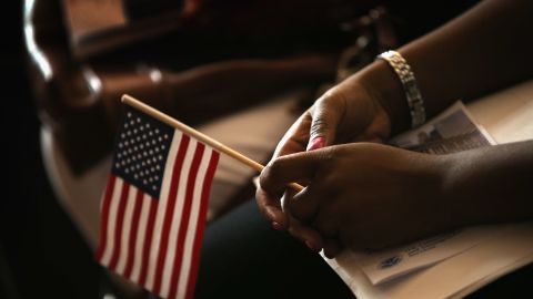 A new U.S. citizen holds a flag July 3 along with her citizenship papers. Would-be citizens must pass a civics and history test.