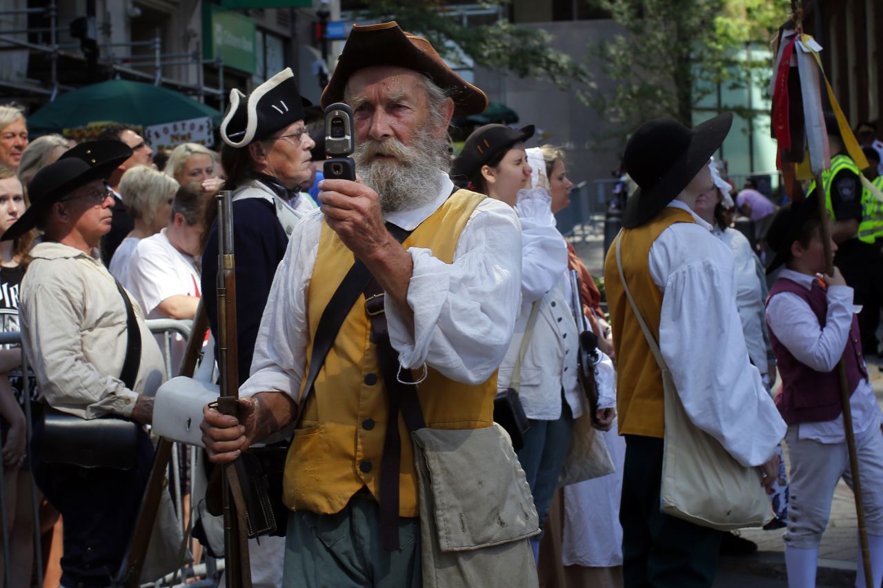 A re-enactor in colonial attire takes a photograph with his mobile phone before a public reading of the Declaration of Independence in Boston.