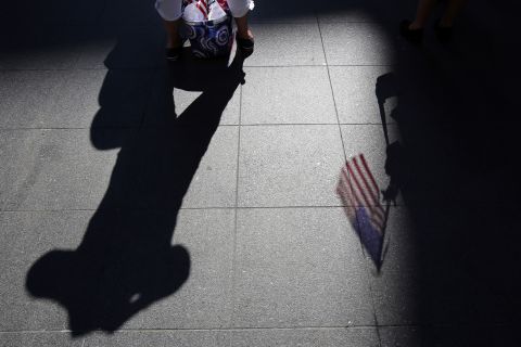 An American flag casts a shadow on the ground as spectators wait for a public reading the Declaration of Independence in Boston.