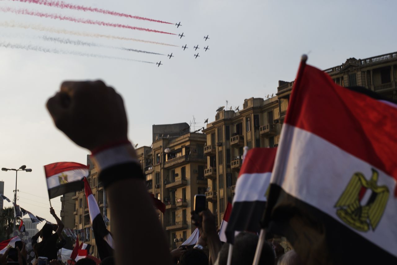 Egyptians cheer and wave national flags as airplanes fly above Tahrir Square on July 4, leaving a trail of smoke in the colors of the national flag.