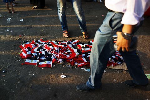 People walk by a pile of Egyptian flags for sale in Tahrir Square on July 4.
