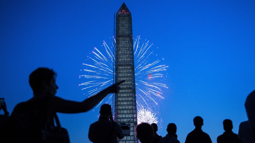 People watch fireworks burst behind the Washington Monument on the National Mall July 4, 2013 in Washington, DC.
