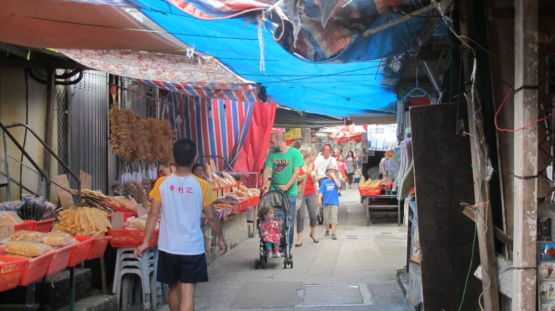 Tourists walk down Tai O's main street, where locals operates seafood stores and souvenir shops.
