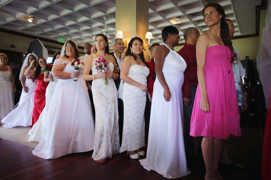 Brides line up with their grooms during a group Valentine's Day wedding at the National Croquet Center on February 14, 2013, in West Palm Beach, Florida. The group wedding is put on by the Palm Beach Country Clerk & Comptroller's office, and approximately 40 couples tied the knot. 