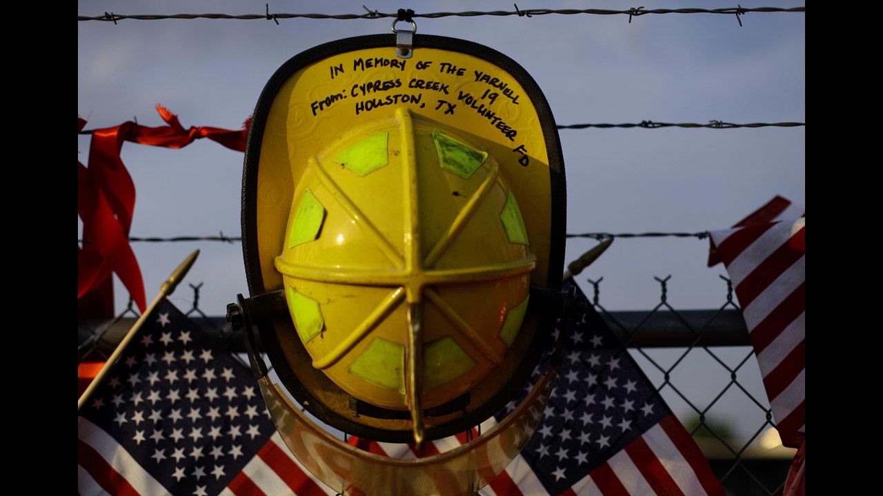 A firefighter's helmet from a Texas volunteer department hangs on a fence at a makeshift memorial to the fallen Granite Mountain Hotshots in Prescott on July 4.