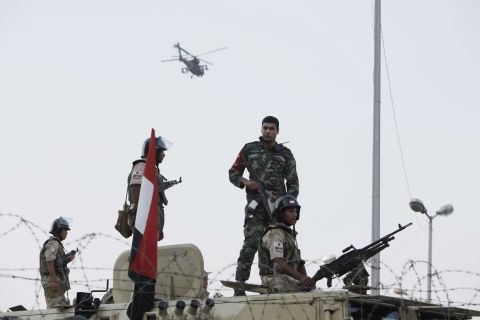 Egyptian Army soldiers stand guard at the Cairo headquarters of the Republican Guard on July 5 as an Apache attack helicopter flies overhead.