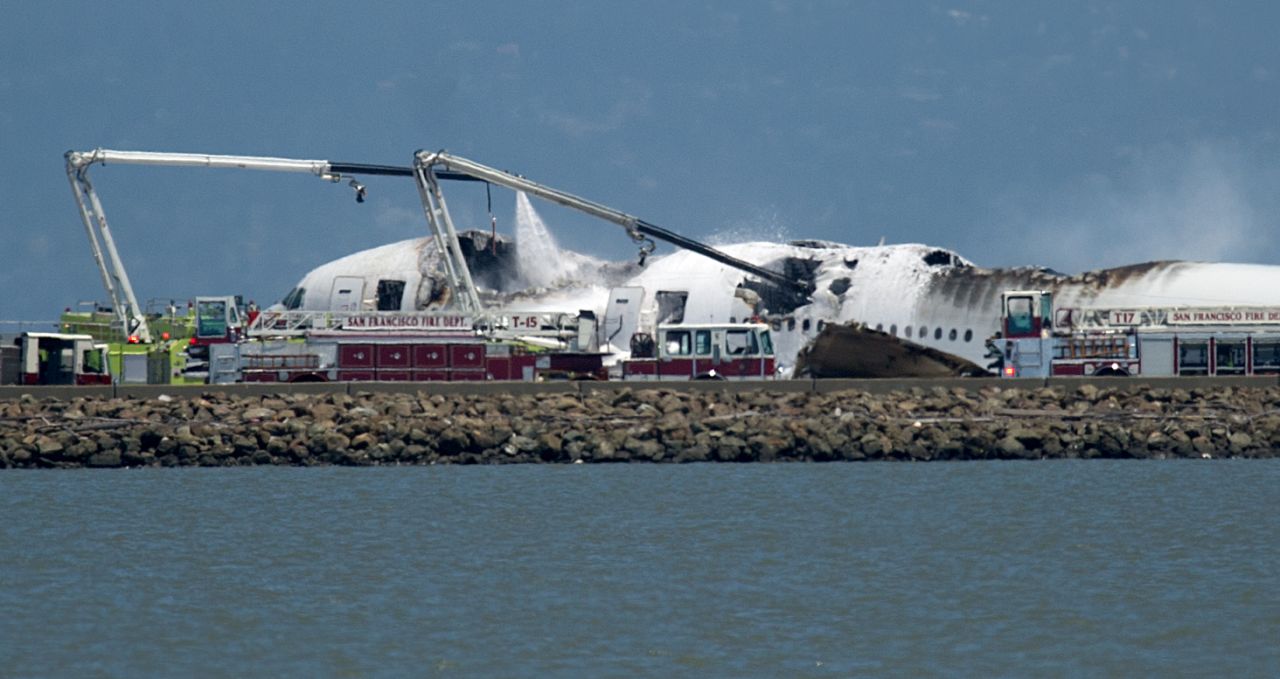 Un camión de bomberos echa agua sobre los restos calcinados del avión.
