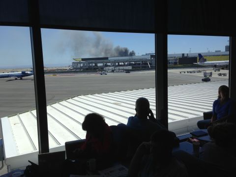 iReporter Val Vaden captured this photo while waiting in a departure lounge at the San Francisco airport on July 6. Val observed the billowing smoke and emergency responders' rush in. 