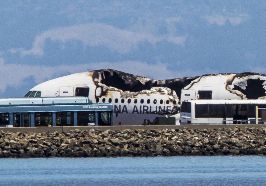 Airport shuttles arrive on the scene after the crash landing.