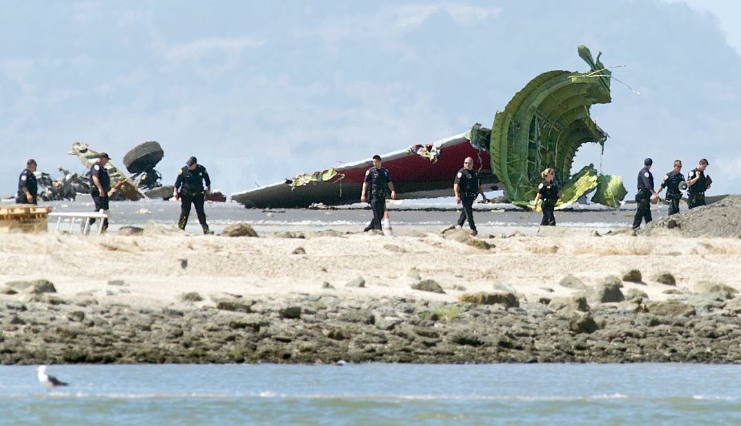 Investigators pass the detached tail and landing gear of Asiana Airlines Flight 214 on July 6.