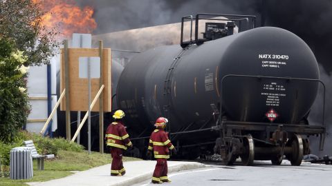 Firefighters walk past derailed cars on July 6.