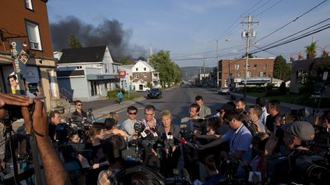 Smoke rises in the background as Quebec Premier Pauline Marois speaks to reporters in Lac-Megantic on July 6.