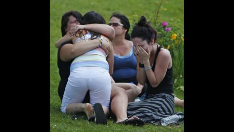 People cry and hug each other on July 7 while they sit on the grass at the Polyvalente Montignac, the school sheltering the people who were forced to leave their houses.