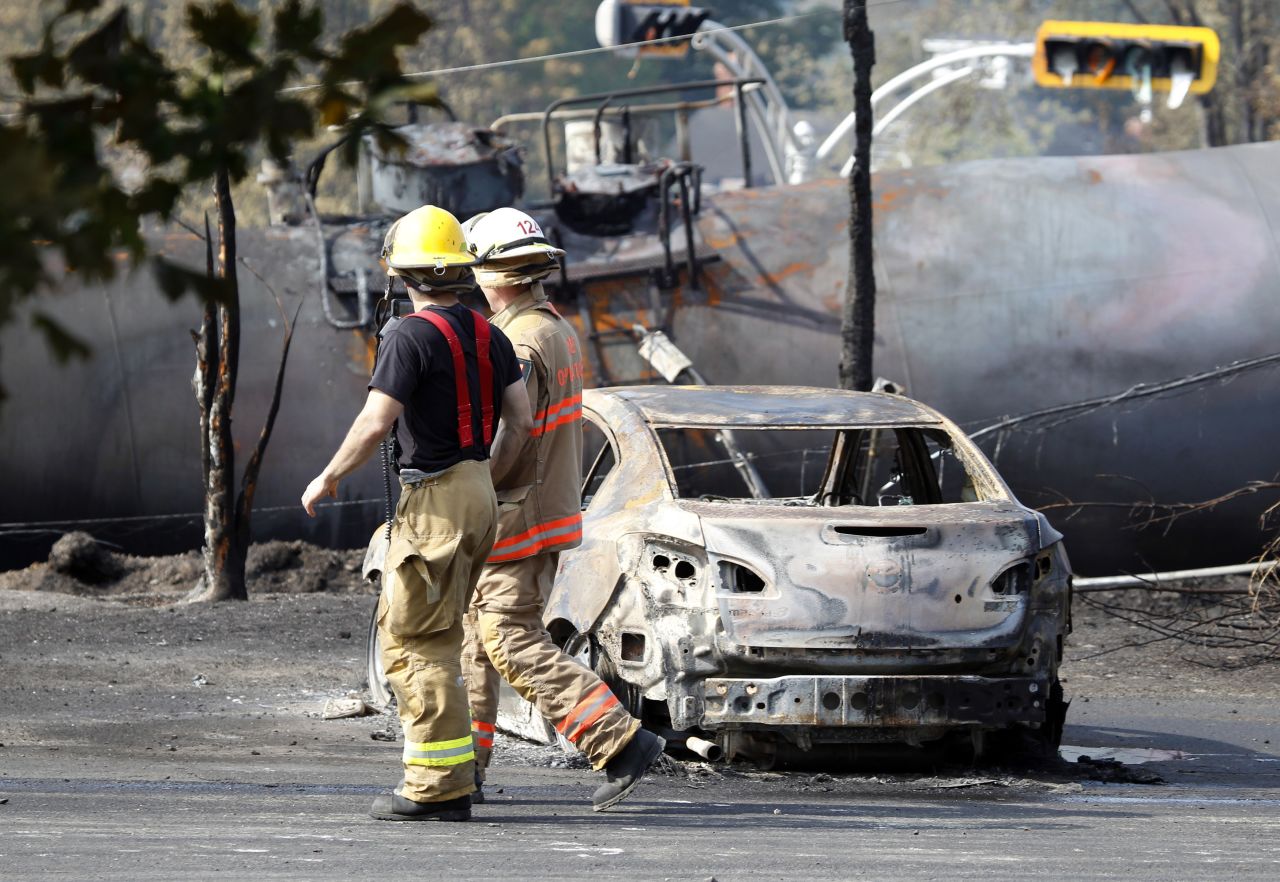 Firefighters walk past a burnt out vehicle near the train derailment in Lac Megantic, Quebec, July 7.